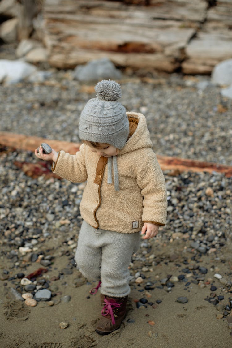 Curious Little Girl In Warm Clothing Walking On Winter Beach