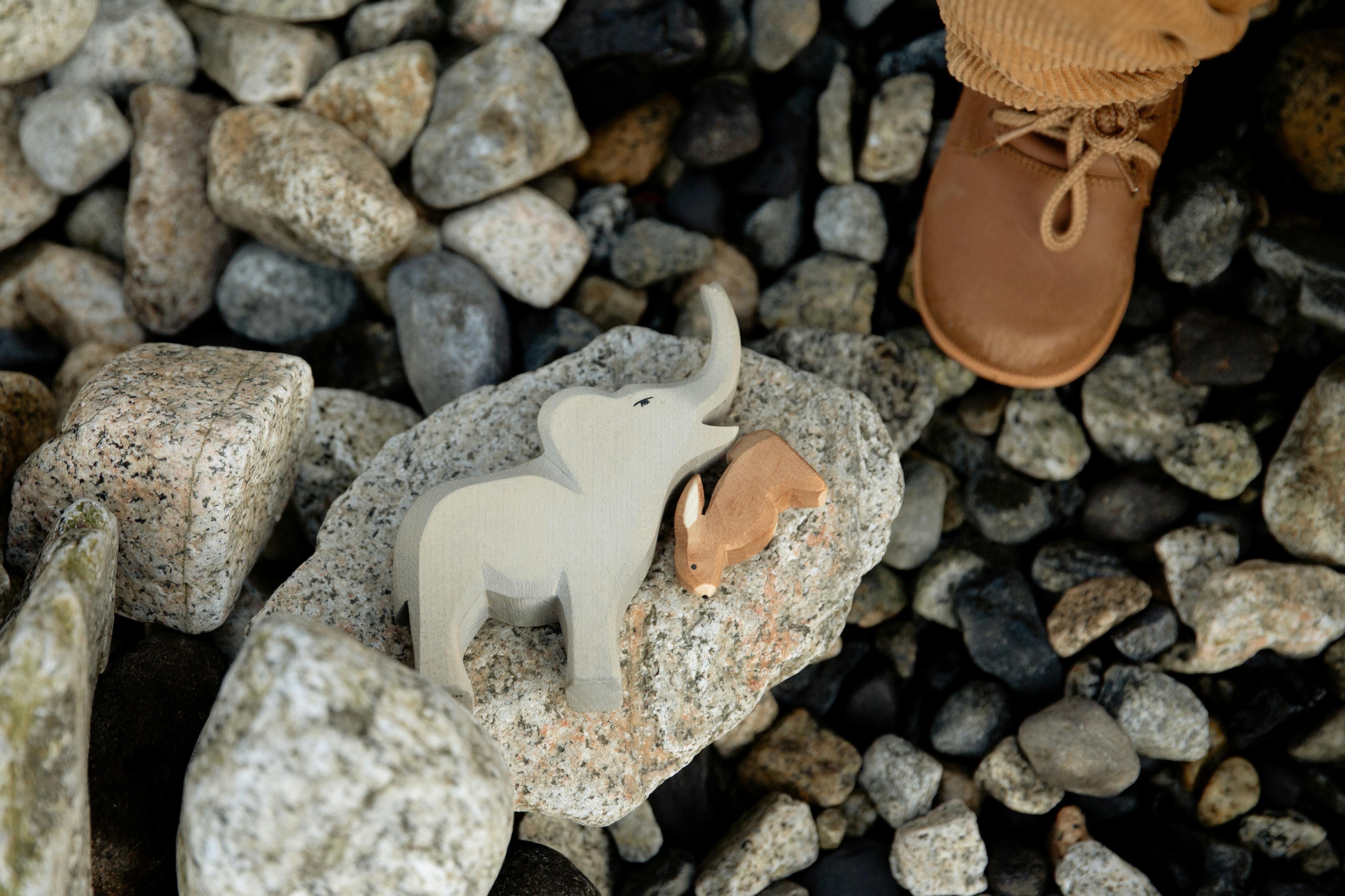 faceless child playing with animal toys on rocky coast