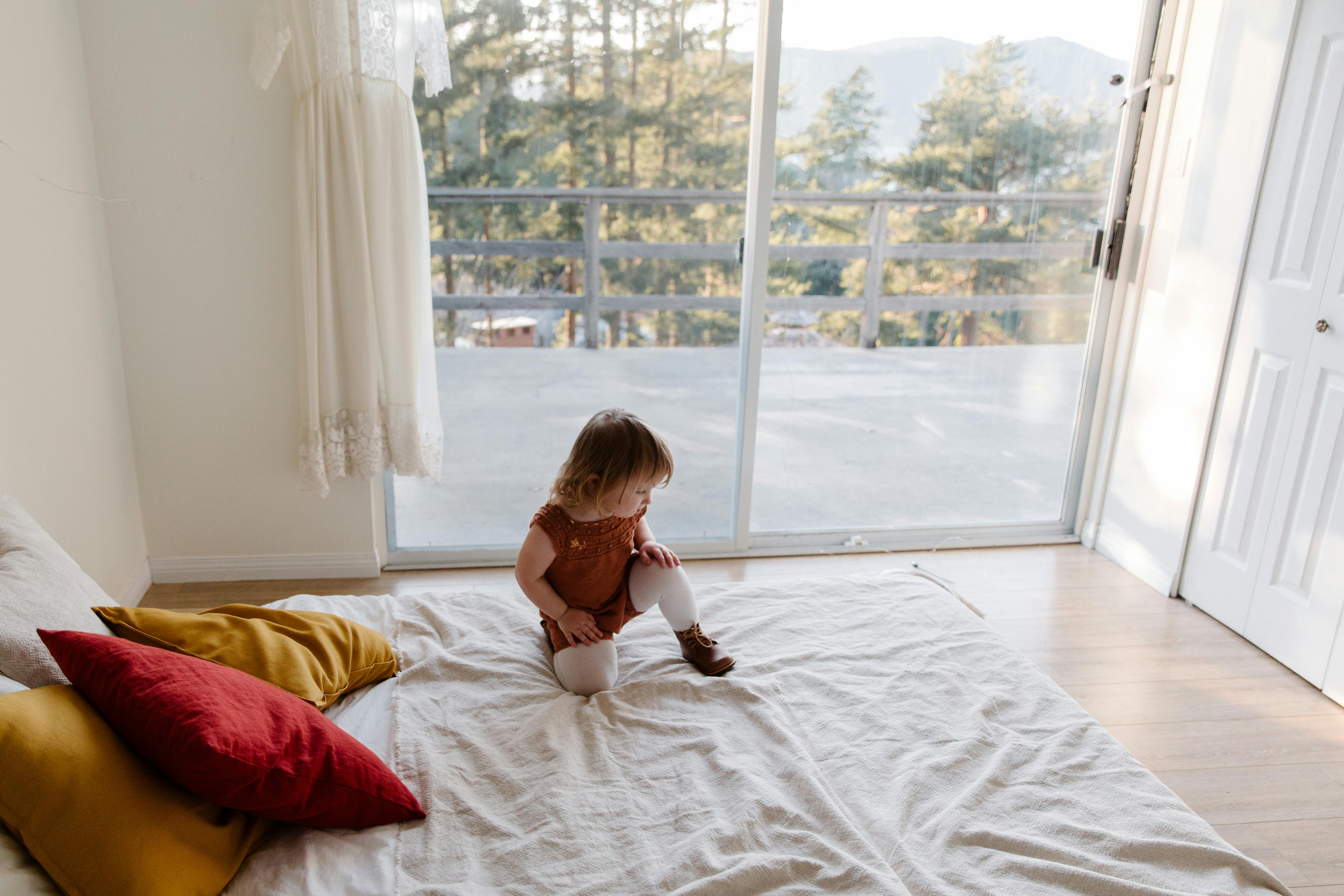 Cute preschool girl dancing on wide bed in spacious bedroom · Free Stock Photo