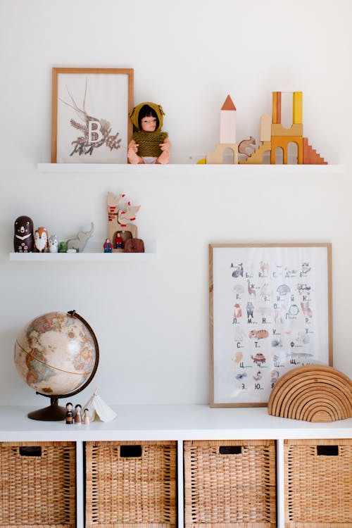 Vintage glove on cabinet with toys and paintings on shelves at home