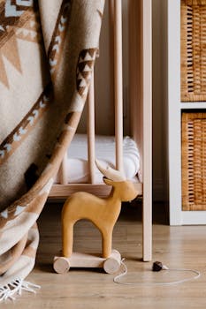 从上面看，家里明亮的托儿所中，地板上放着一只木鹿玩具，它身上有绳子，正躺在舒适的格子床上