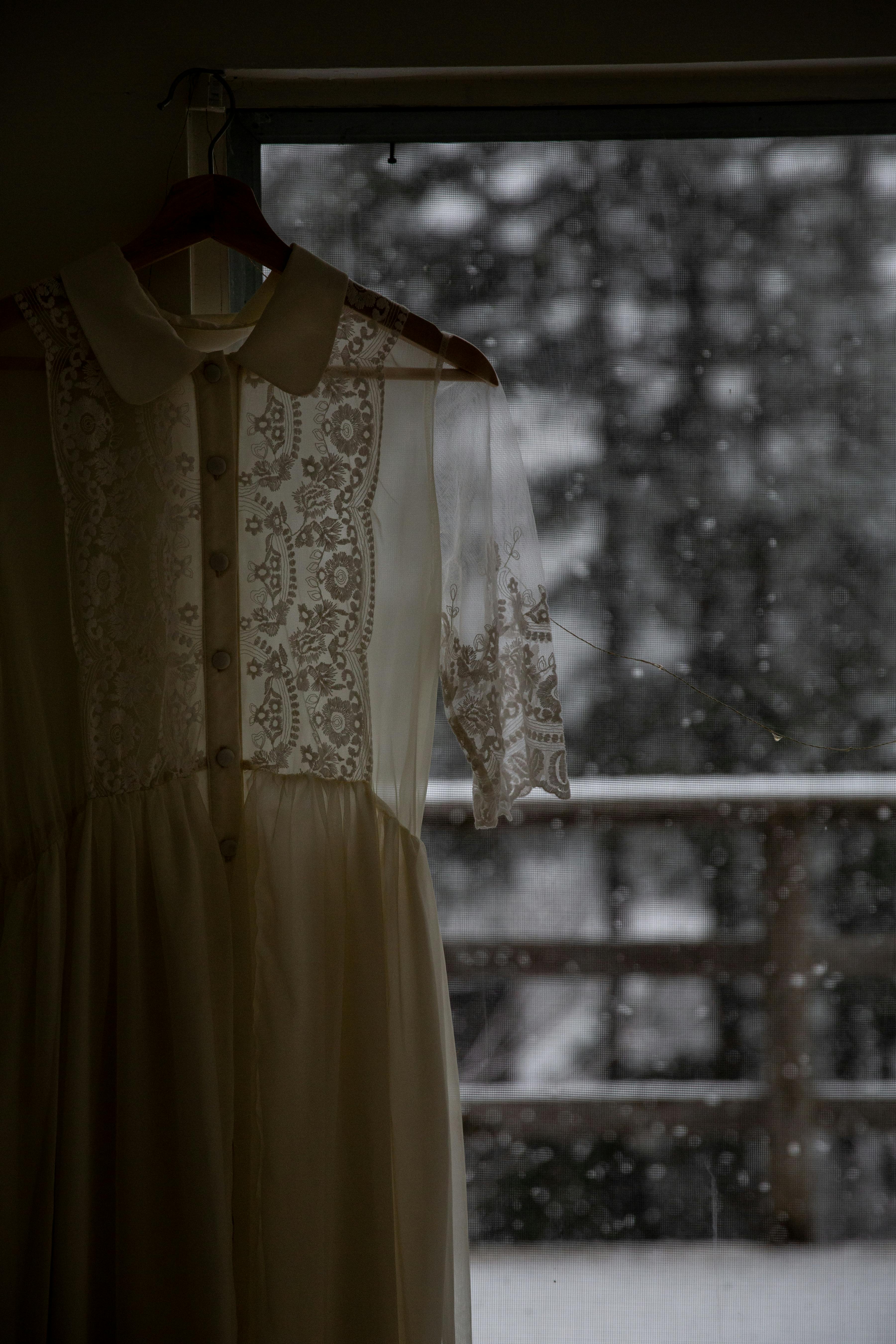 vintage dress hanging on hanger near window in rainy day