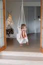 一个孩子在室内波西米亚秋千上，享受着平静的时刻，周围是舒适的室内设计
