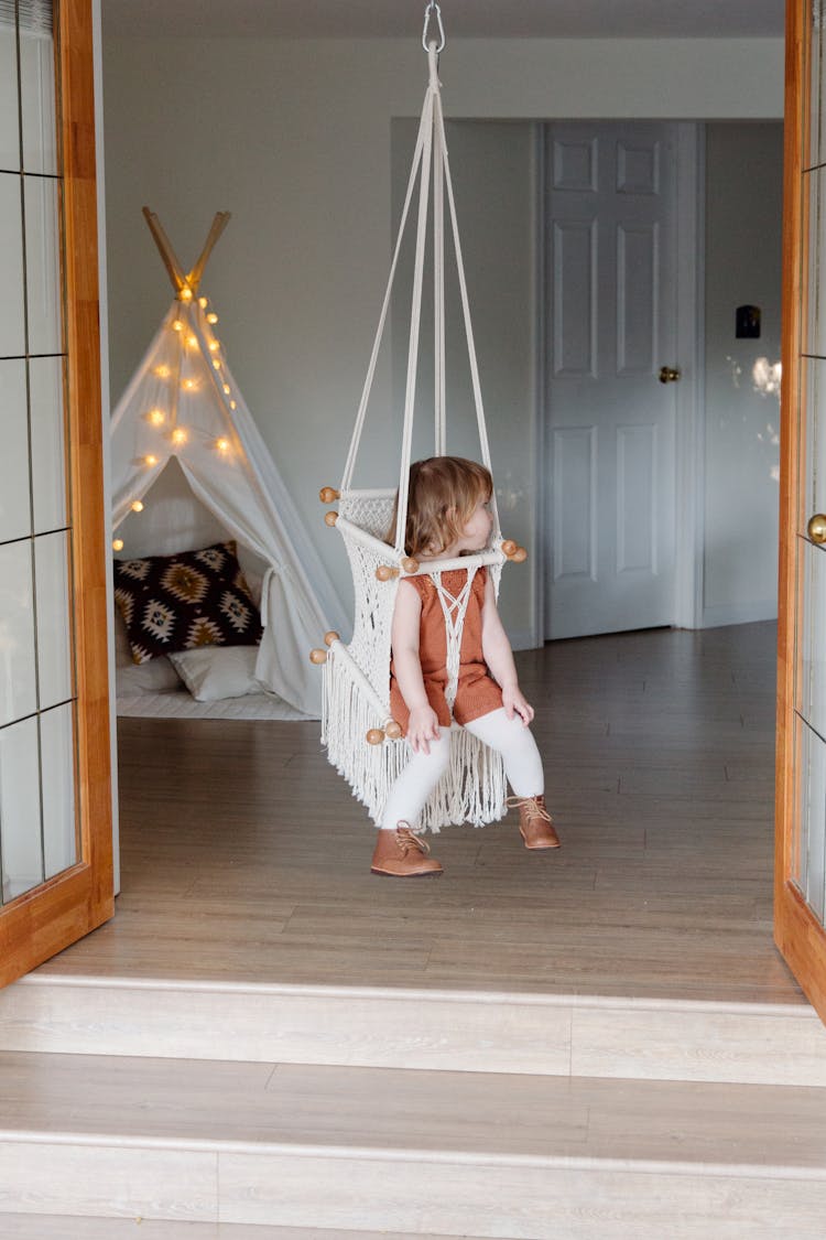 Little Girl Resting On Swing In Cozy Room