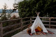 这座波西米亚风格的帐篷配有地毯和枕头，坐落于带木栅栏的露台上，可欣赏到海洋、森林和山脉的如画风景