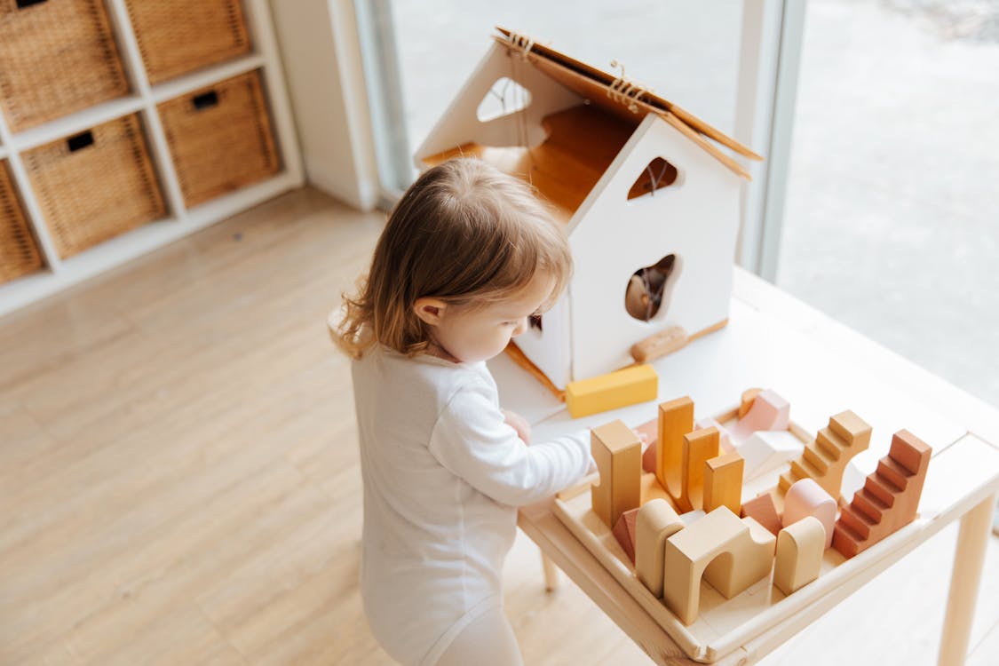 Free Little girl playing with toys at table near window at home Stock Photo