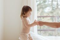 室内光线柔和，一名幼儿与一名成年人牵着手