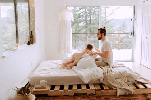 Warm indoor scene of father and child enjoying quality time on a cozy bed, capturing love and togetherness.