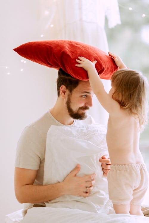 A Father and his Child Playing with Pillows