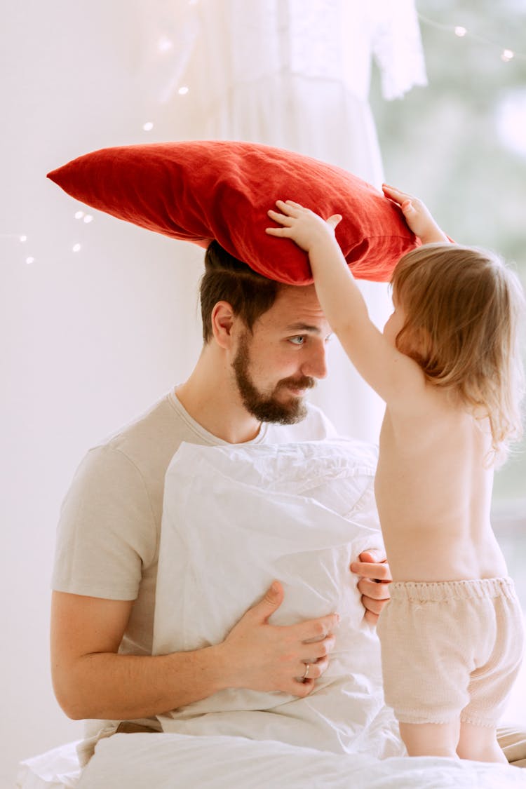 A Father And His Child Playing With Pillows