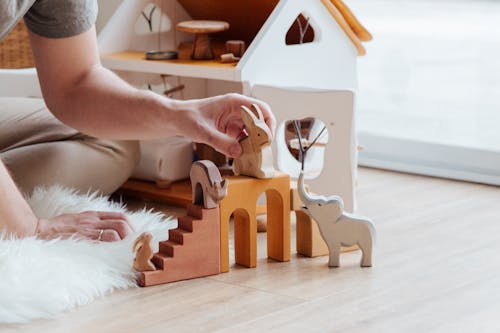 Anonymous crop parent playing with toys on floor at home