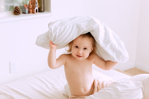 Free  Baby Sitting on Bed With Pillow On Her Head Stock Photo