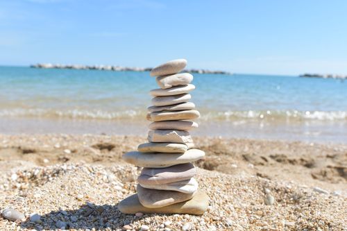Free Stone cairn on a sandy beach with a clear blue sea in Porto Recanati, Italy. Stock Photo