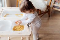 一个年幼的孩子在室内玩干意大利面，感受它的纹理