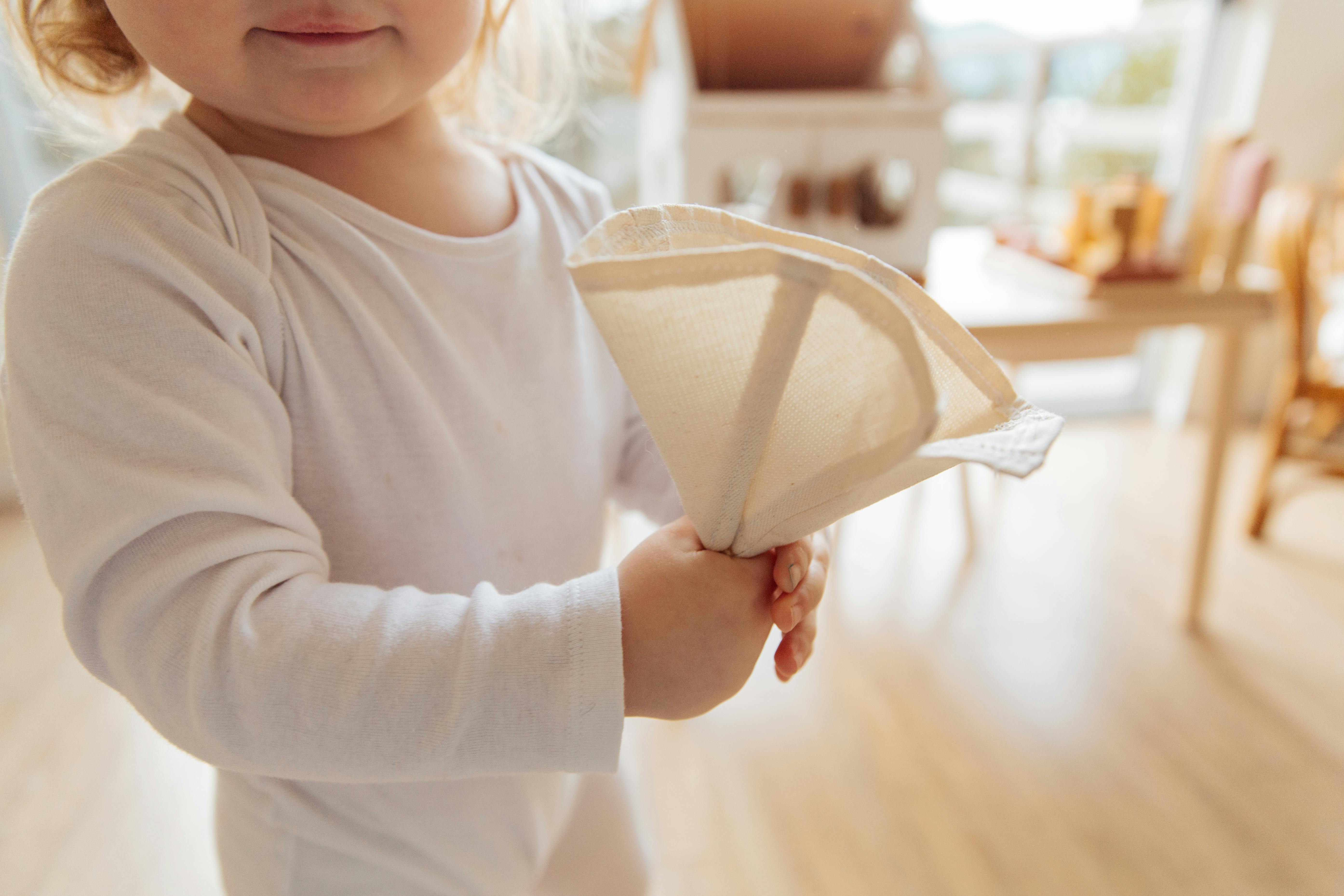 girl in white long sleeve romper holding white paper