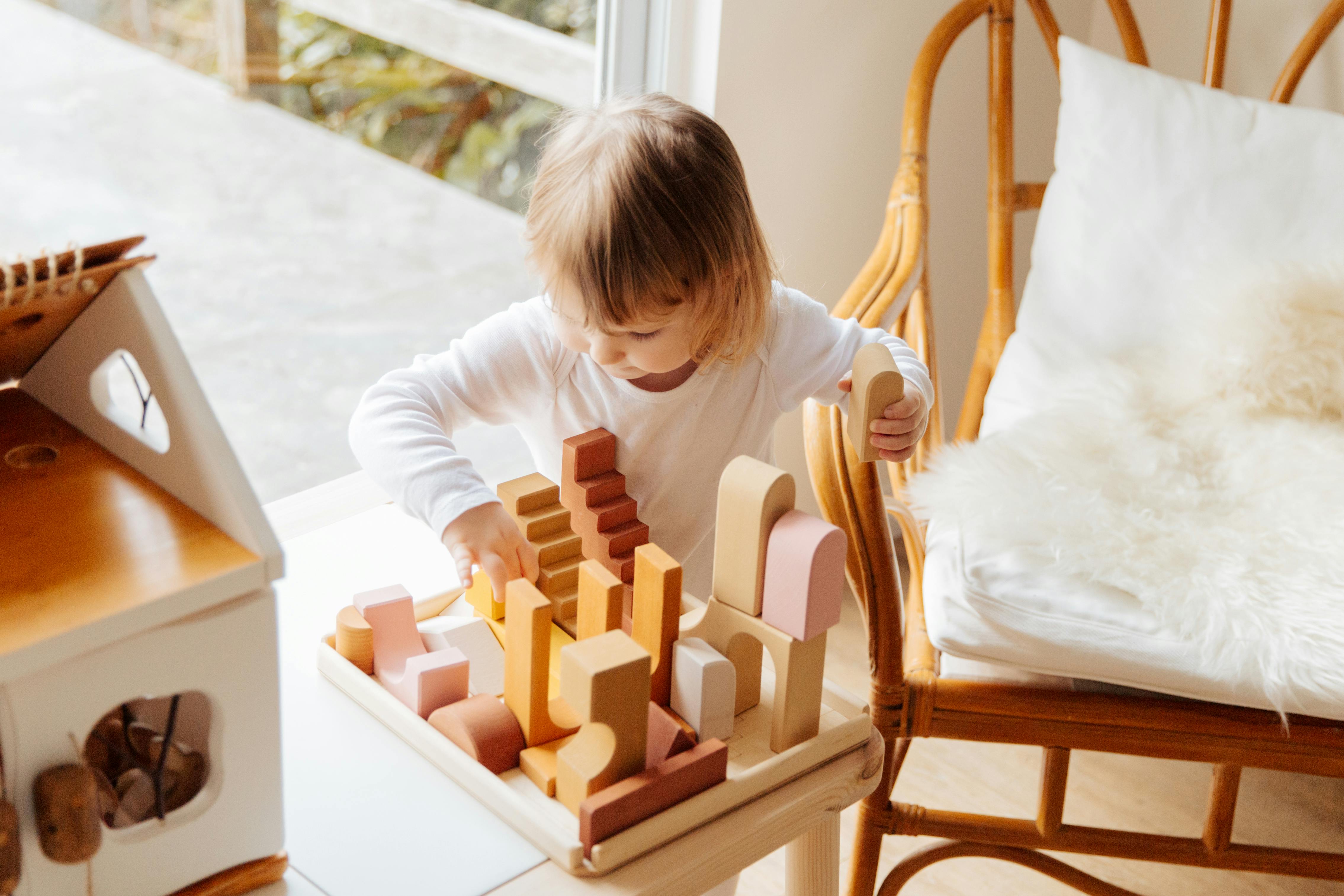 photo of child playing with wooden blocks