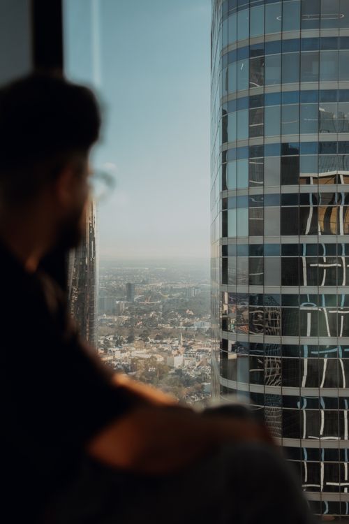 Free A person looks out over the Melbourne skyline from a high-rise window, capturing a modern urban view. Stock Photo