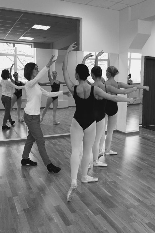 Free Ballet dancers receive guidance from an instructor in a bright dance studio. Stock Photo