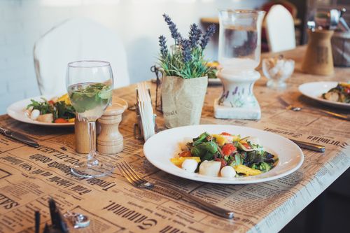 Free Fresh salad with vibrant ingredients on a beautifully set table, perfect for a cozy dining experience. Stock Photo