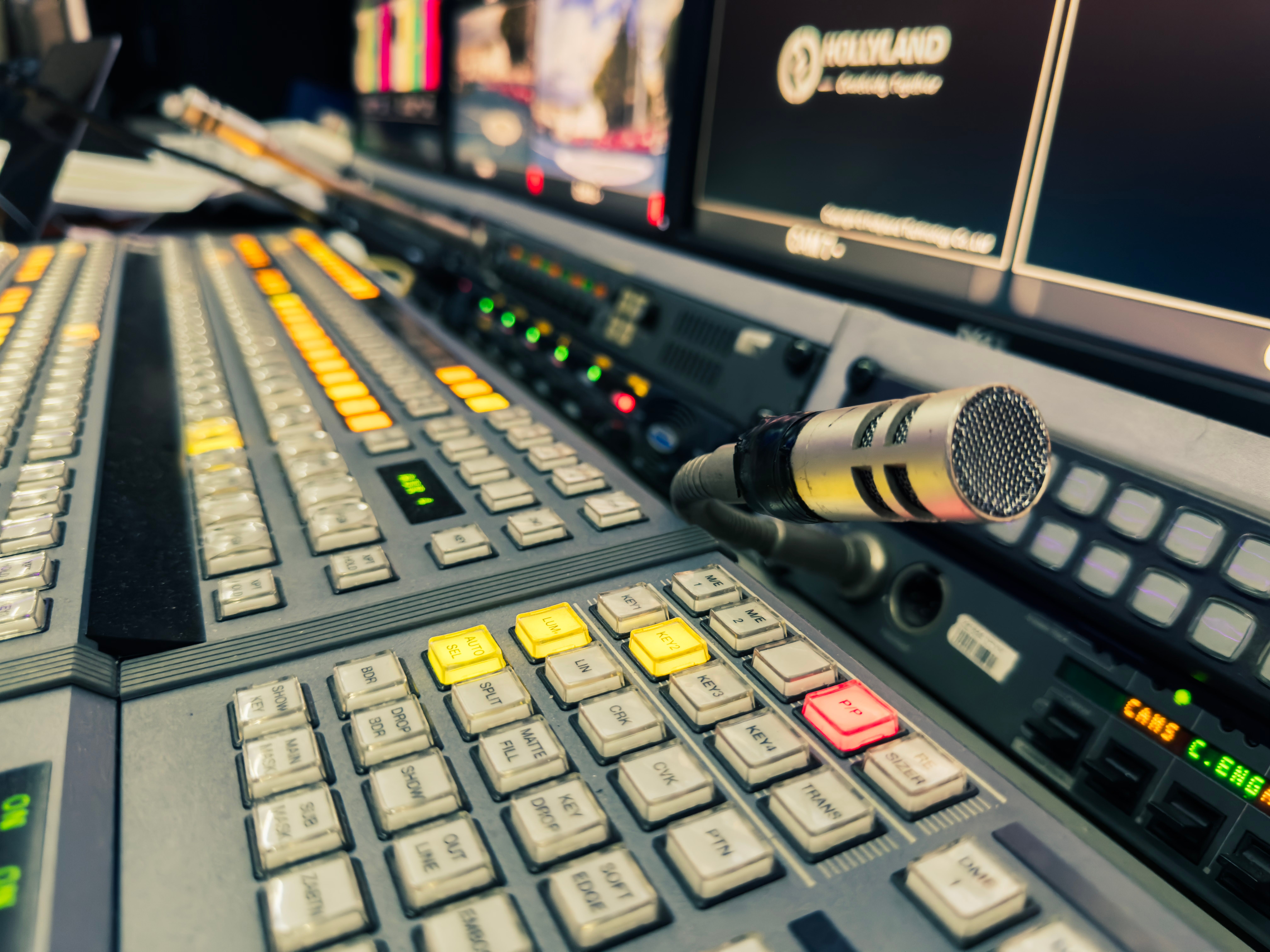 Detailed view of a broadcasting studio control panel with a microphone and multiple screens.