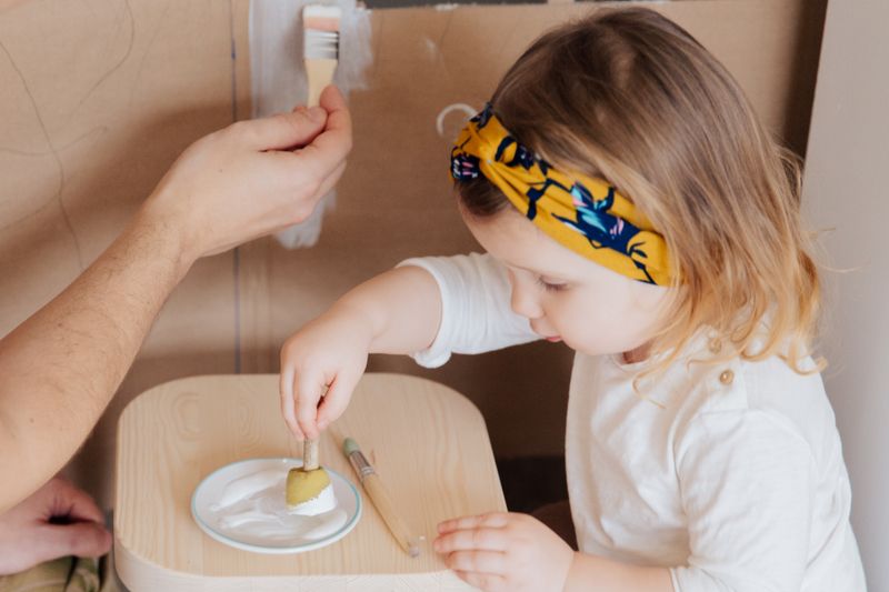 A toddler painting with a sponge