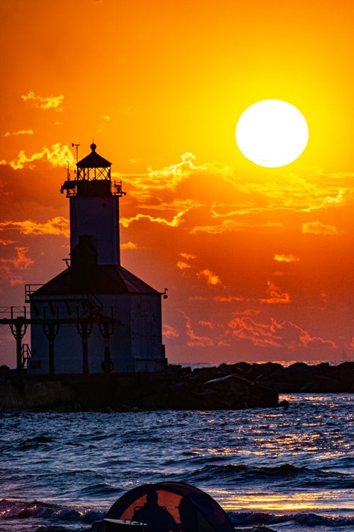 Free Vibrant sunset at Michigan City Lighthouse silhouetted against a dramatic sky. Stock Photo