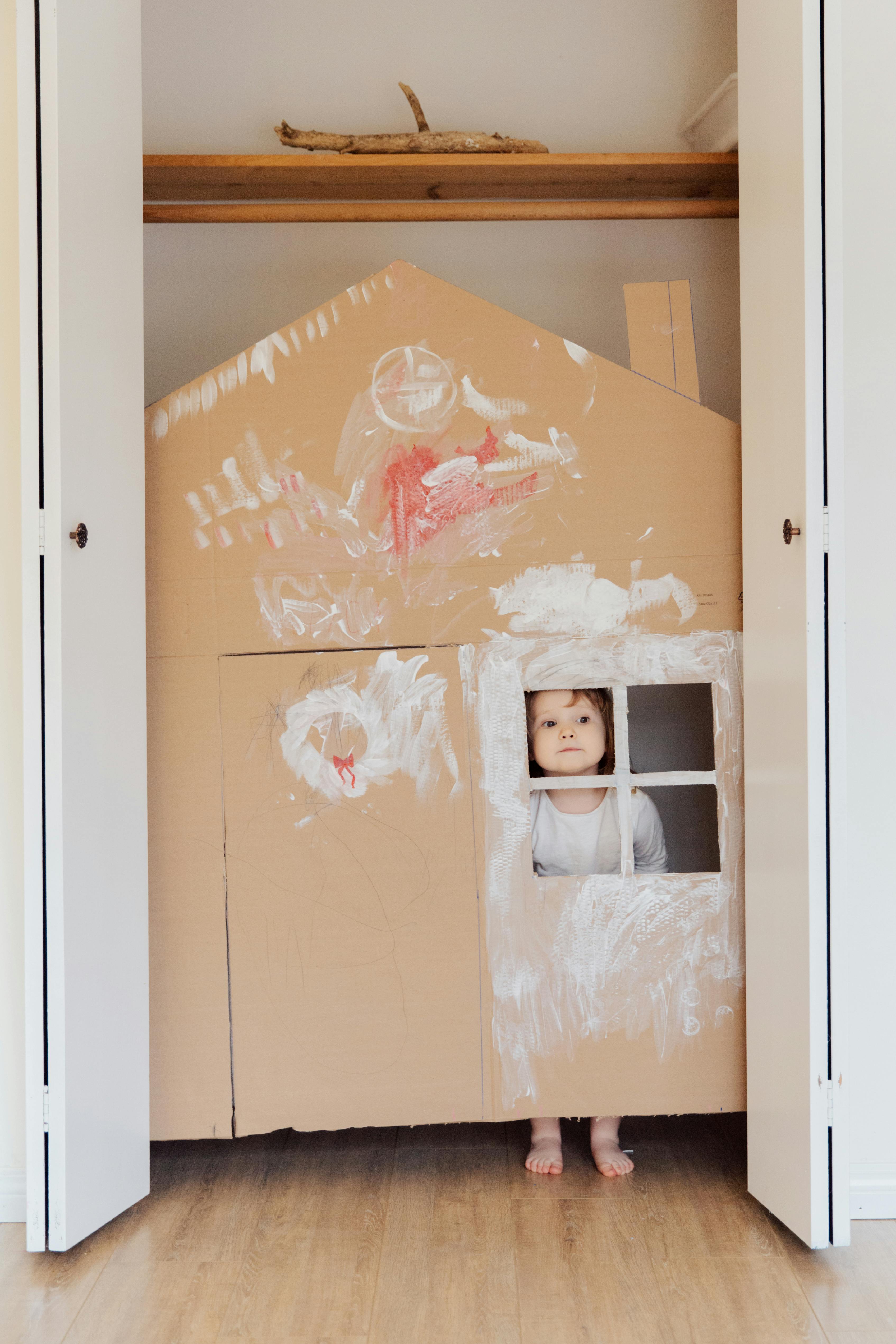 photo of child inside on cardboard house