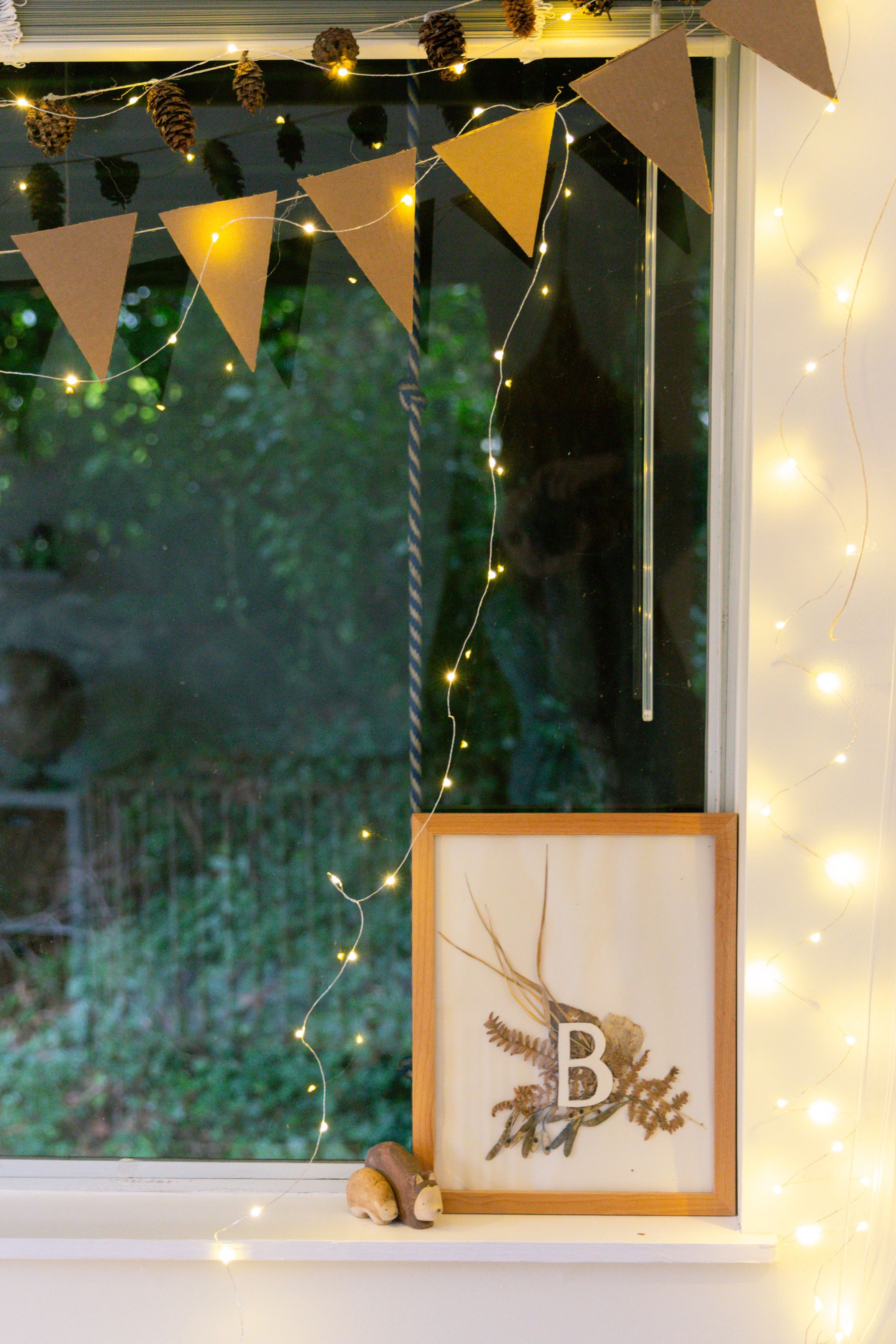 Window decorated with handmade paper ornaments and pinecones