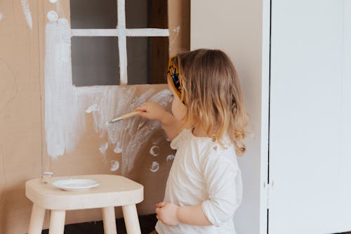 Girl in White Shirt Painting on Cardboard Play House