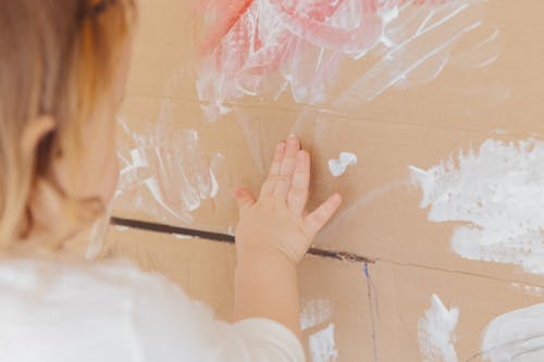 Free Crop anonymous child drawing with white paint at home Stock Photo