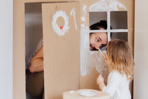 Free A Little Girl and her Dad Painting a Cardboard House  Stock Photo
