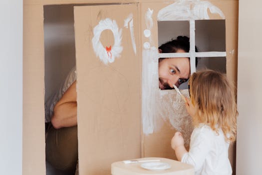 Father and daughter enjoying creative bonding by painting a cardboard playhouse indoors.