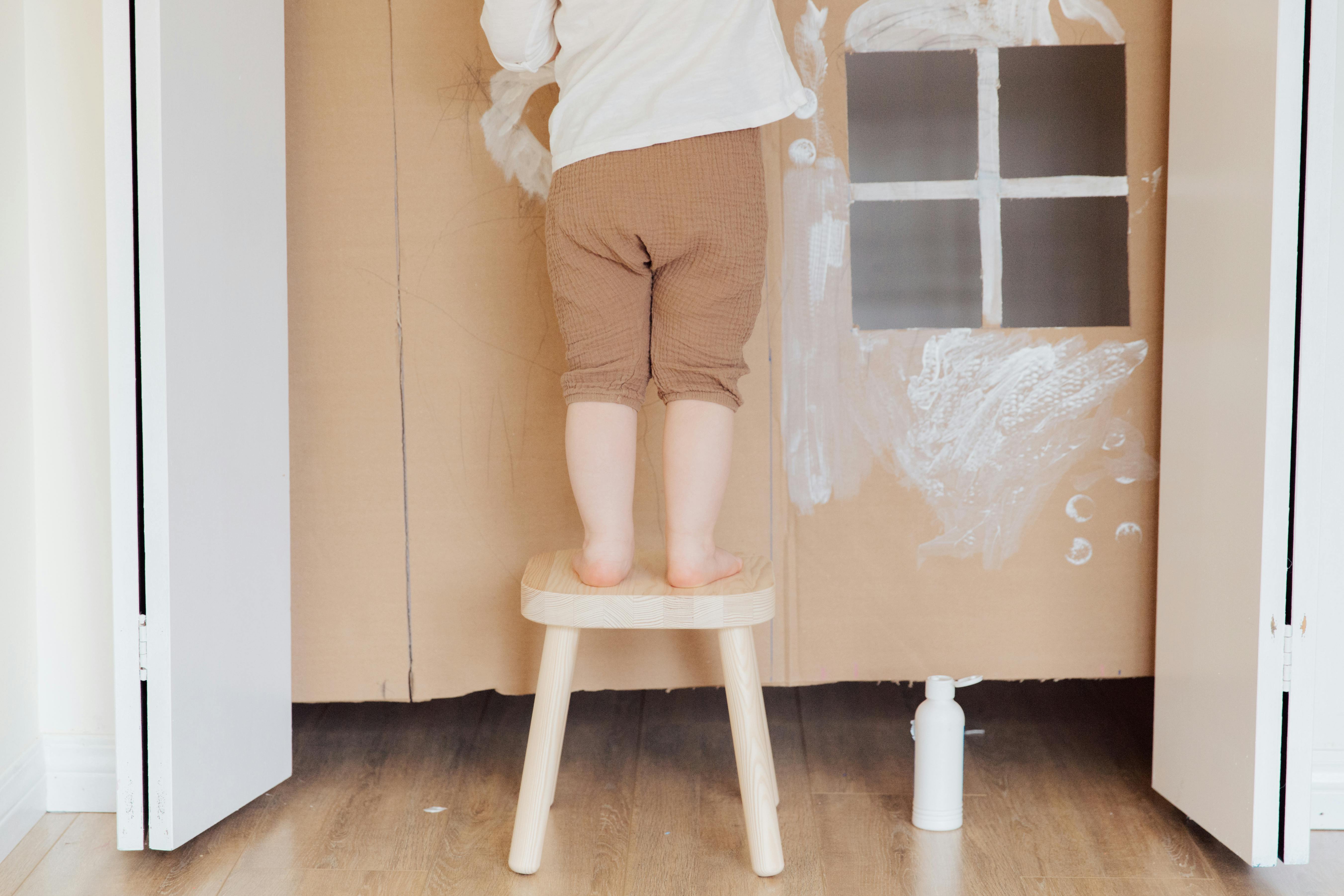 photo of child standing on wooden stool