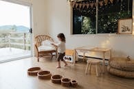 孩子在光线充足、舒适的游戏室里玩耍，里面有木制玩具和装饰