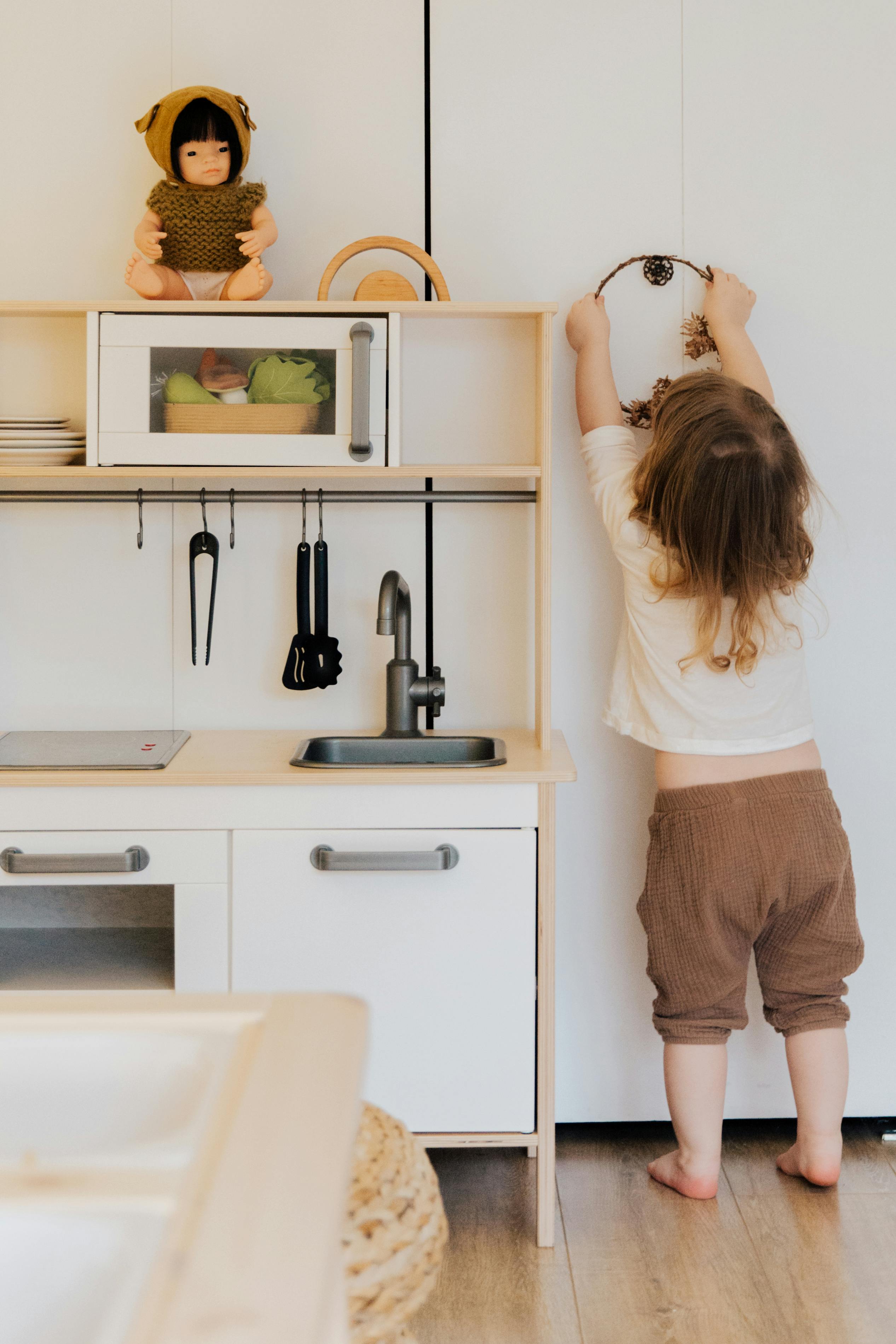 woman in white t shirt and brown pants standing in front of kitchen sink