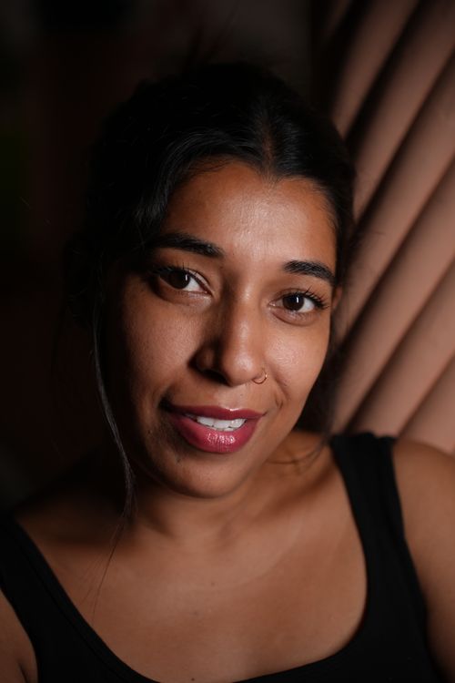 Free A close-up portrait of a woman smiling warmly under soft lighting indoors. Stock Photo