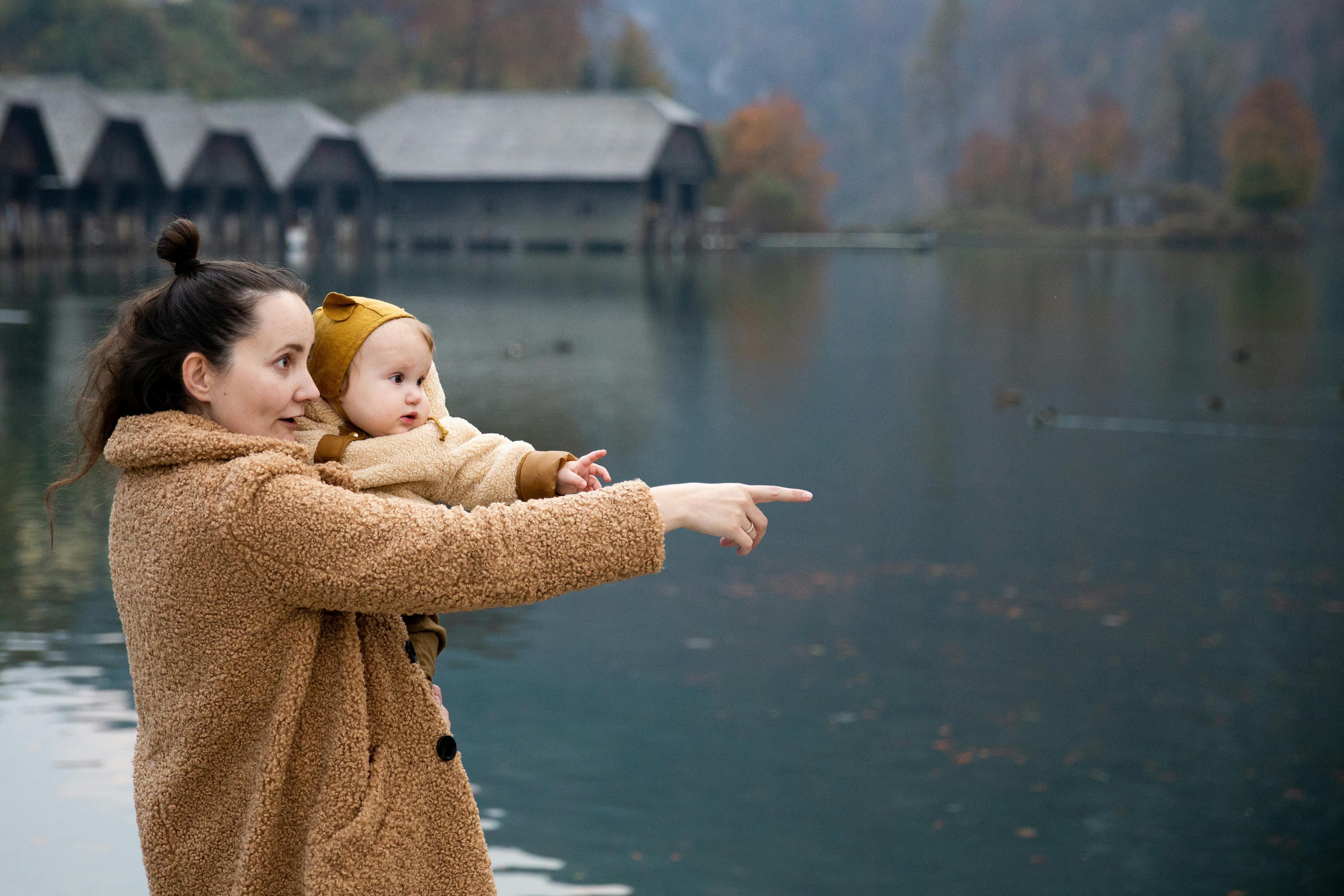 photo of woman carrying baby