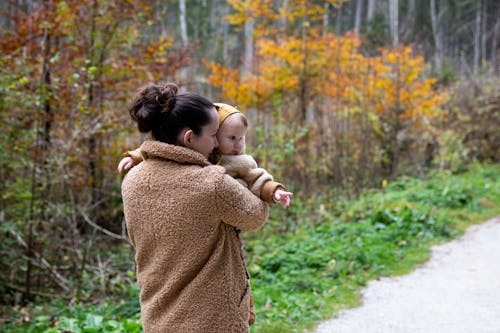 Woman in Brown Sweater Carrying Baby in Brown Sweater