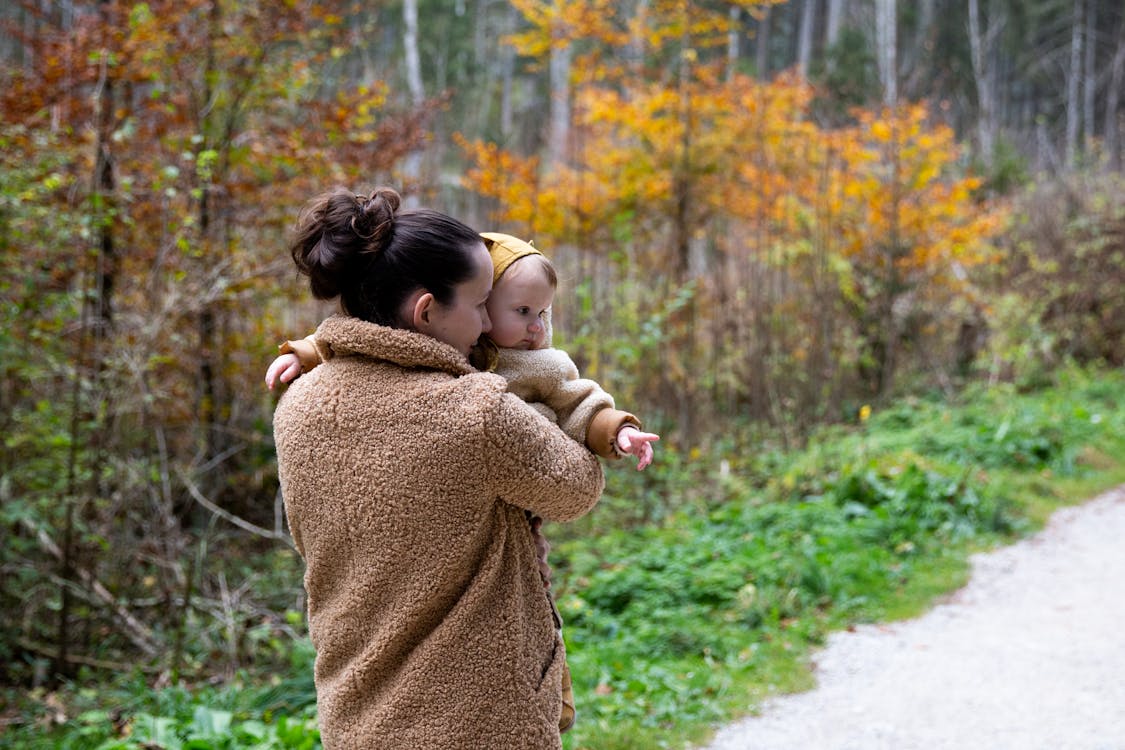 Woman in Brown Sweater Carrying Baby in Brown Sweater