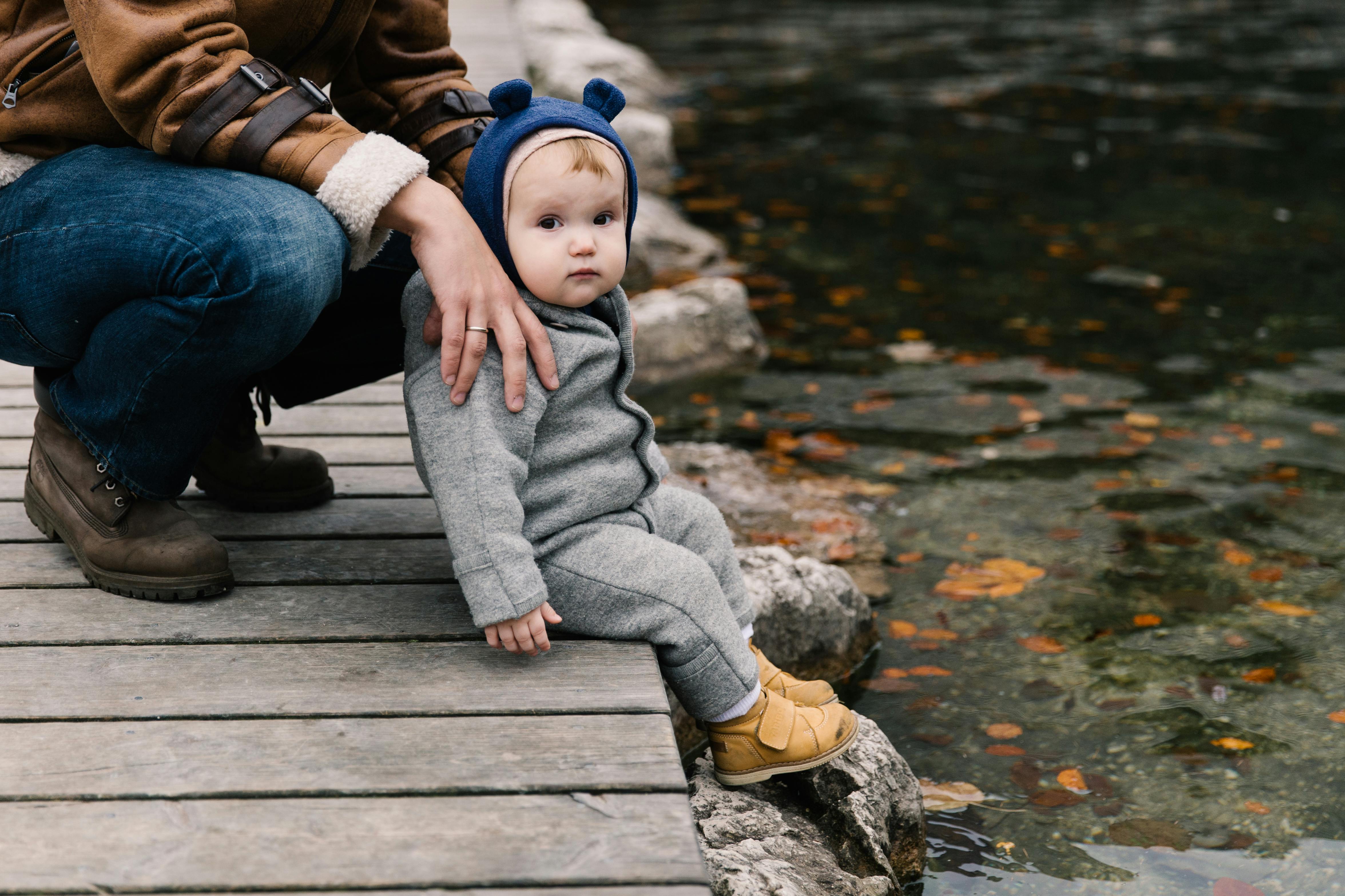 photo of toddler sitting on wooden dock