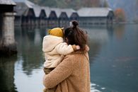 在宁静的湖边，母亲和孩子相拥，展现了大自然中的爱与团结