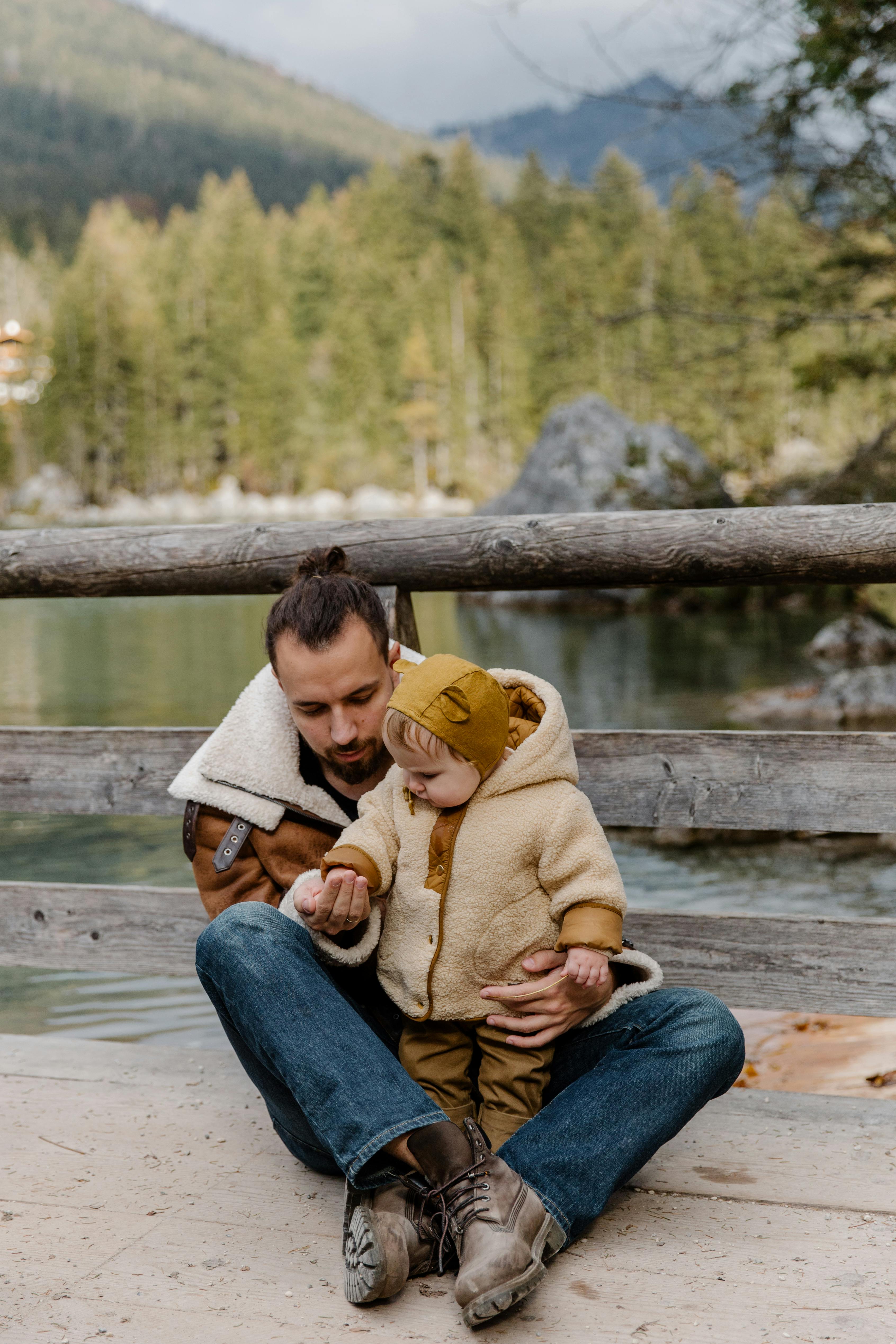 photo of man holding child s arms