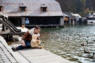 父亲和孩子在湖边的码头上，与鸭子共度亲密时光