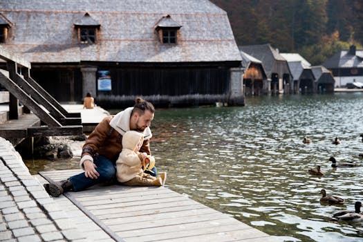 父亲和孩子在湖边的码头上，与鸭子共度亲密时光