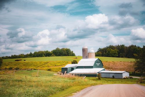Free Beautiful countryside farm with a barn and silo under a cloudy sky. Perfect for rural and agricultural themes. Stock Photo