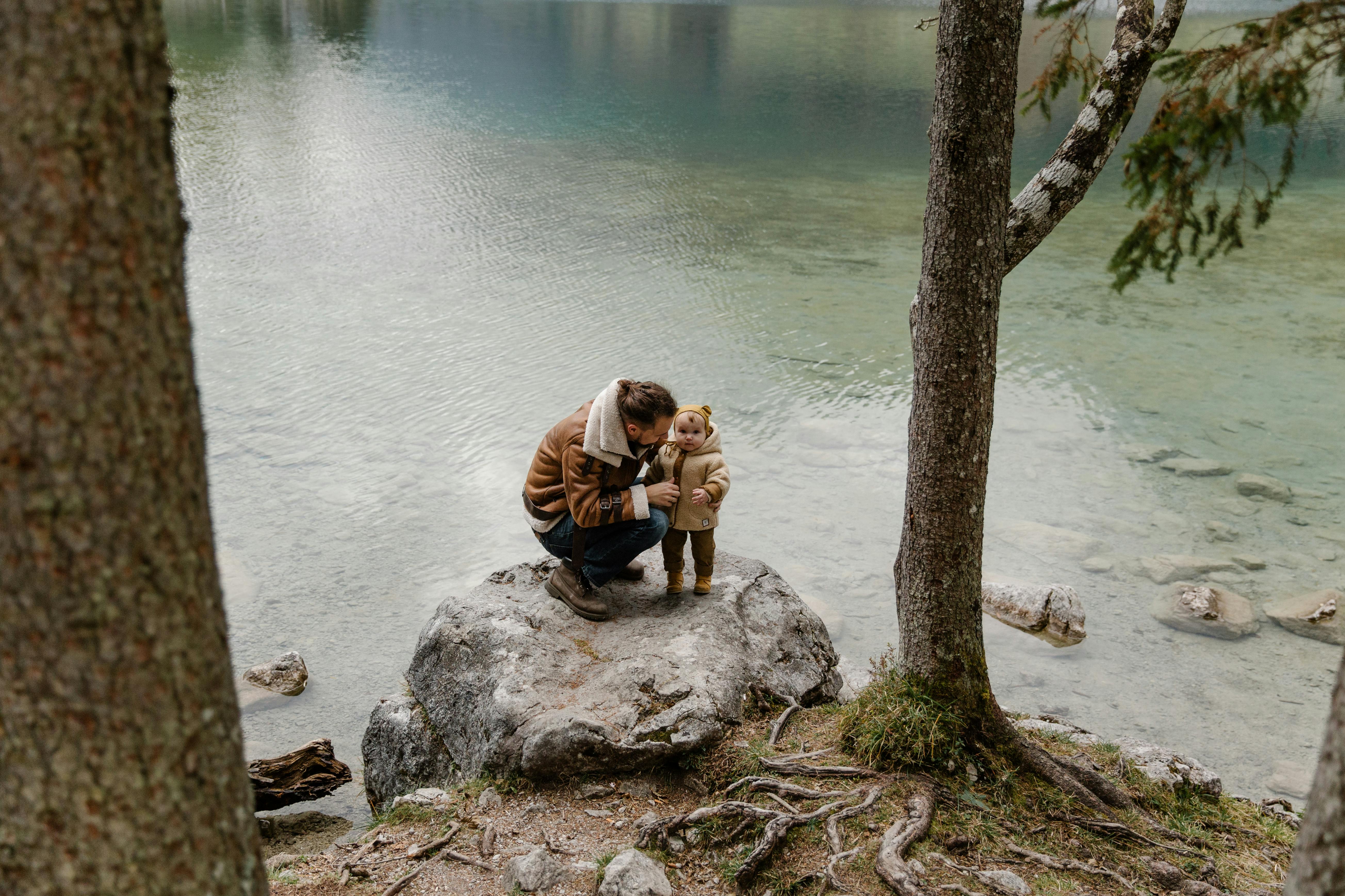 photo of man and baby standing on rock