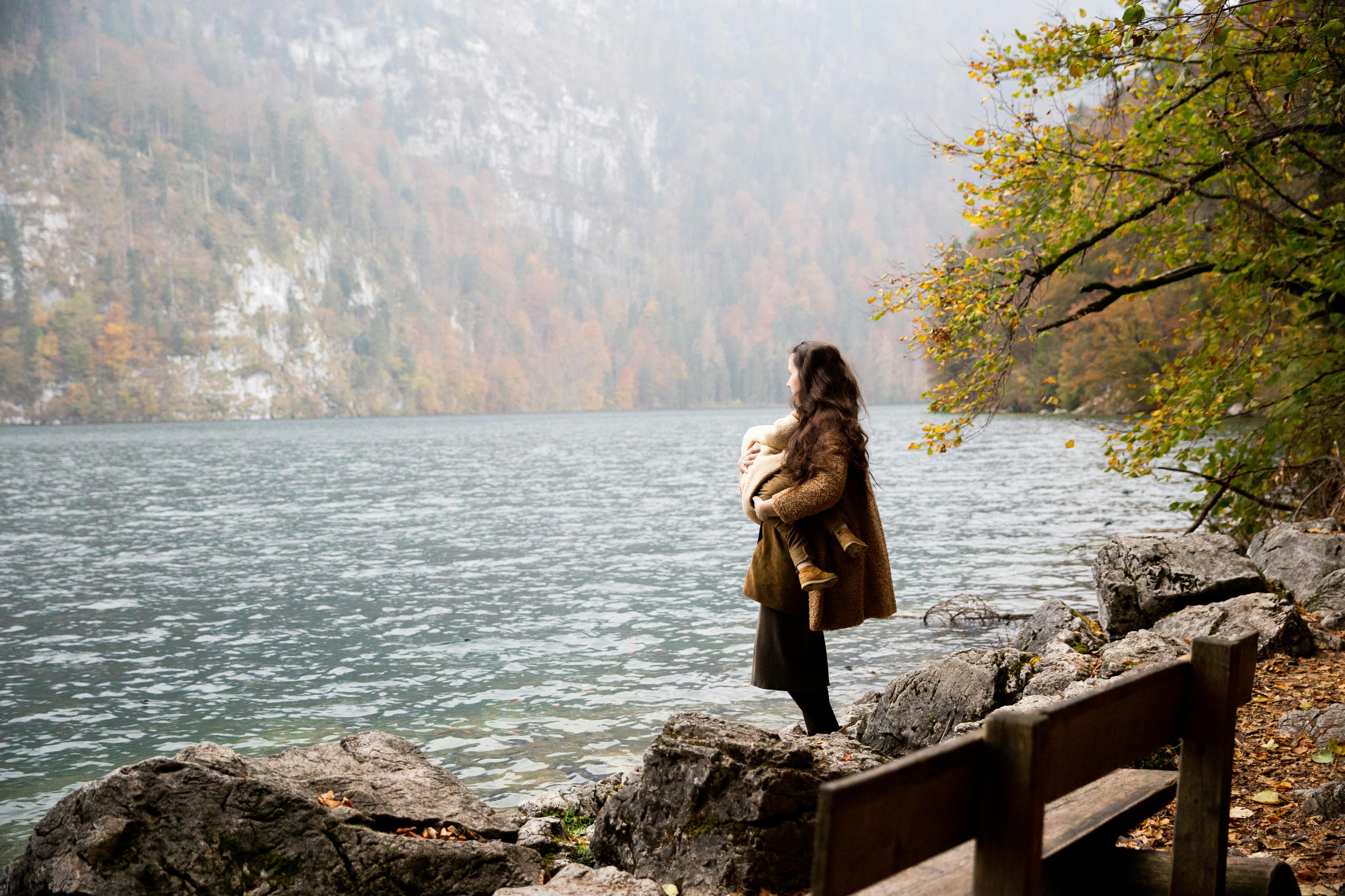 photo of woman carrying baby