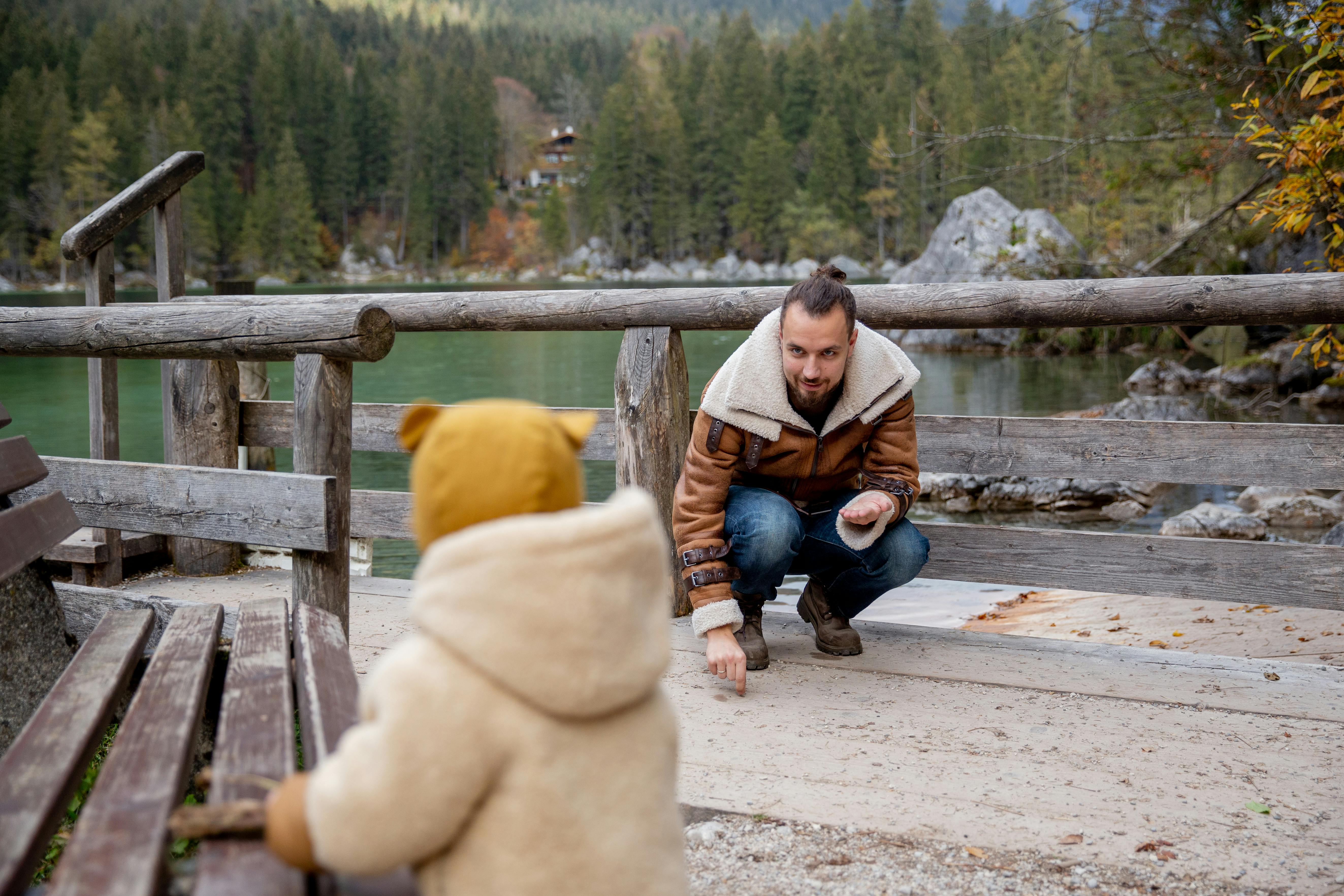 男人和孩子在风景秀丽的湖边，被大自然包围，穿着温暖的衣服