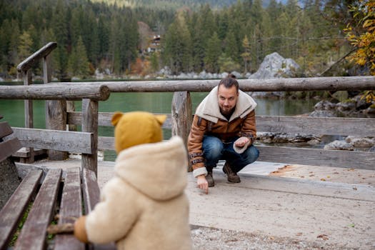 男人和孩子在风景秀丽的湖边，被大自然包围，穿着温暖的衣服