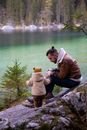 父亲和蹒跚学步的孩子在风景如画的湖边，于郁郁葱葱的绿树间享受宁静的时刻
